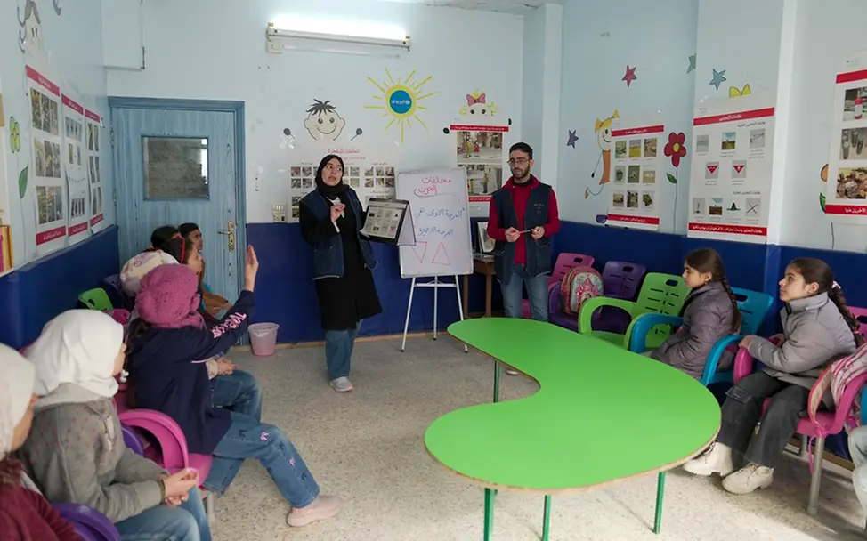 Syrien: Kinder sitzen um einen Schreibtisch in einem kinderfreundlichen Zentrum