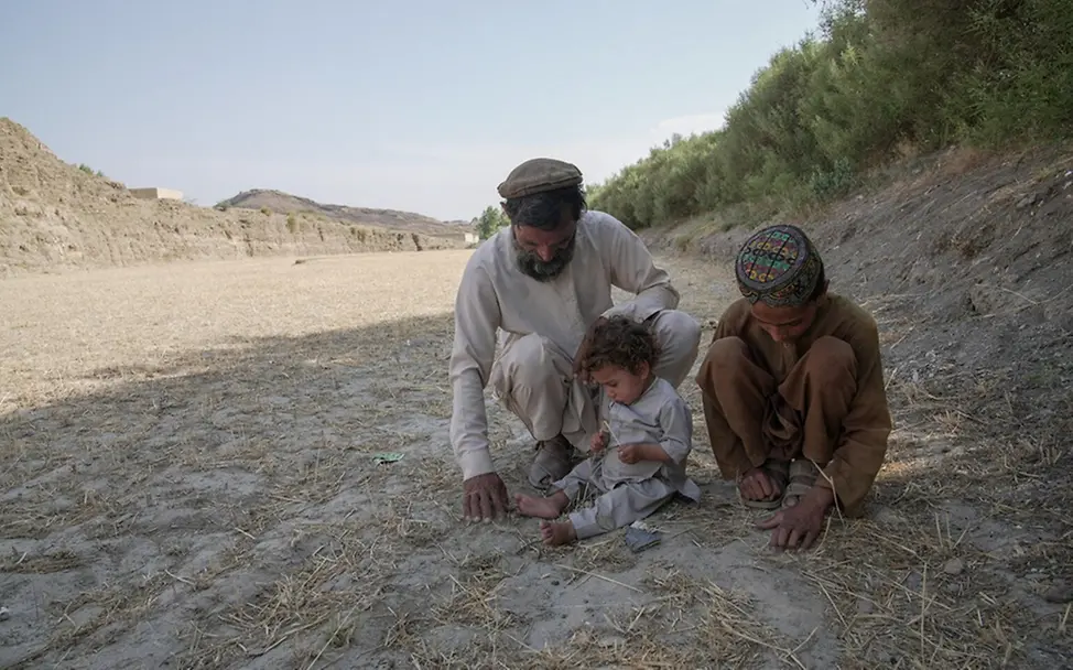 Dürre: Folgen für Kinder & Ursachen: Baitullah, sein kleiner Bruder und sein Vater auf ihrem ausgetrockneten Land.