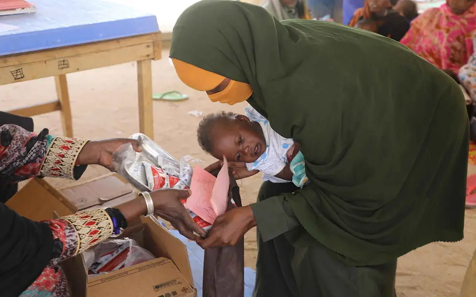 Erdnusspaste spenden: Eine Mutter mit Baby holt eine Ration Erdnusspaste im Gesundheitszentrum ab.