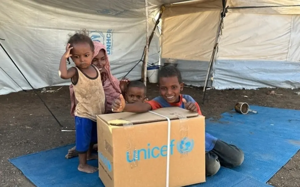 Geflüchtete Familien im Sudan erhalten ein Paket von UNICEF, das ihnen helfen soll.