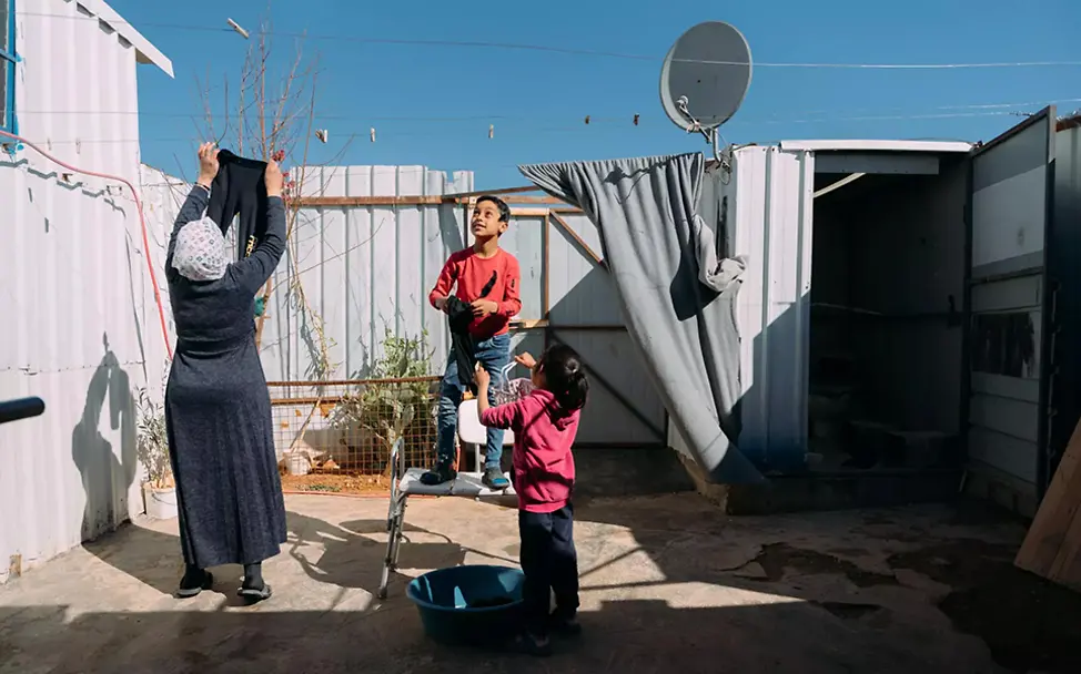 Aus Syrien geflüchtete Familie hängt in einem Flüchtlingscamp gemeinsam Wäsche auf.