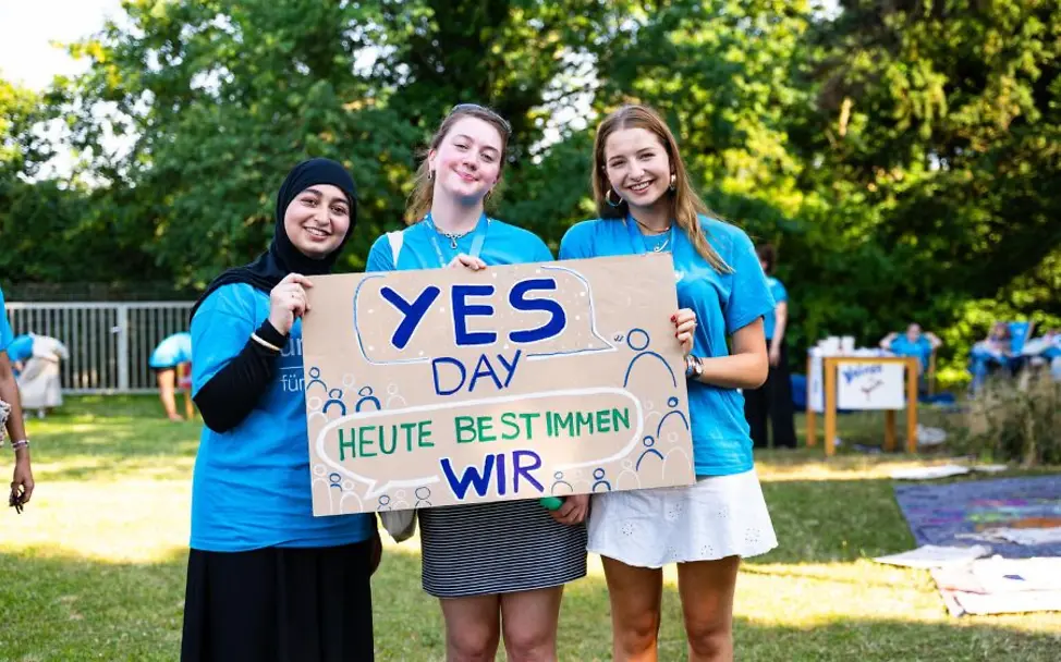 Yes-Day: Gruppe mit Plakat in der Hand. | © UNICEF/UN0890046/Sachse-Grimm Schulaktion zum Tag der Kinderrechte: Drei Mädchen halten ein großes Schild mit der Aufschrift Yes Day.