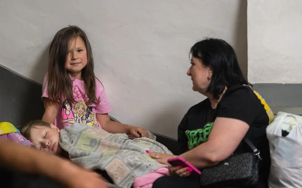 Eine Familie versucht auf der Rolltreppe einer U-Bahn-Station zu schlafen | © UNICEF/Filippov Spende Ukraine Kinder: Eine Familie versucht auf der Rolltreppe einer U-Bahn-Station zu schlafen.