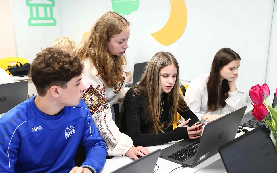 Ukraine Spenden: Eine Lehrerin und Schüler arbeiten in einer unterirdischen Schule an ihren Laptops.