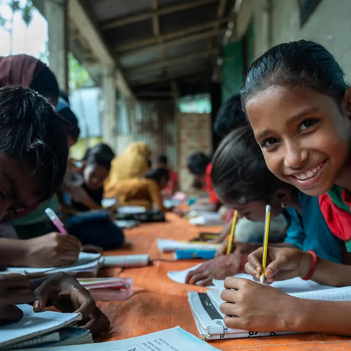 Die Initiative "Let Us Learn" von UNICEF setzt sich dafür ein, dass mehr Kinder in Bangladesch lernen können. | © UNICEF/Himu Bildung in Bangladesch: Kinder schreiben vor einer Schule in ihre Hefte.