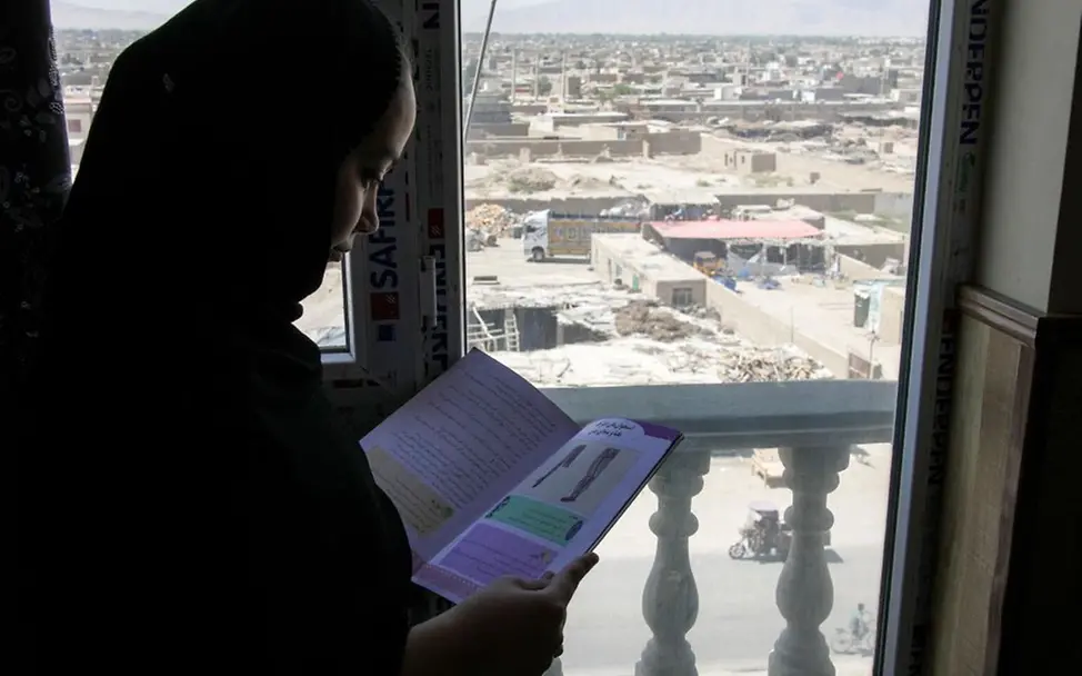 Afghanistan spenden: Ein 14-jähriges Mädchen liest in einem Schulheft.