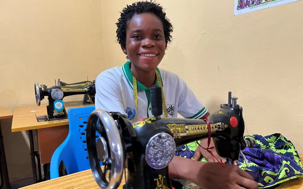 Grundausbildungen in Schneiderei und Gastronomie ermöglichen Jugendlichen in Liberia, ihren Lebensunterhalt selbst zu verdienen. | © UNICEF/Bücker Let Us Learn in Liberia: Ein Mädchen sitzt mit einer Nähmaschine an einem Tisch.