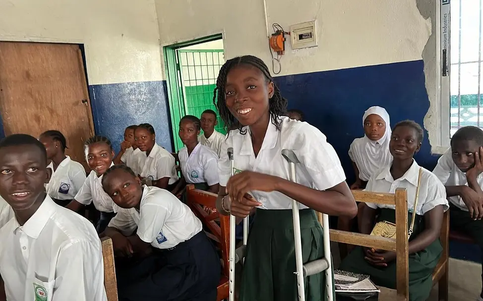 Viele Kinder In Liberia gehen nicht zur Schule oder brechen ihre Ausbildung schon früh ab. | © UNICEF/Bücker Let Us Learn in Liberia: Ein Mädchen auf Krücken steht mit ihren Mitschüler*innen im Klassenzimmer.