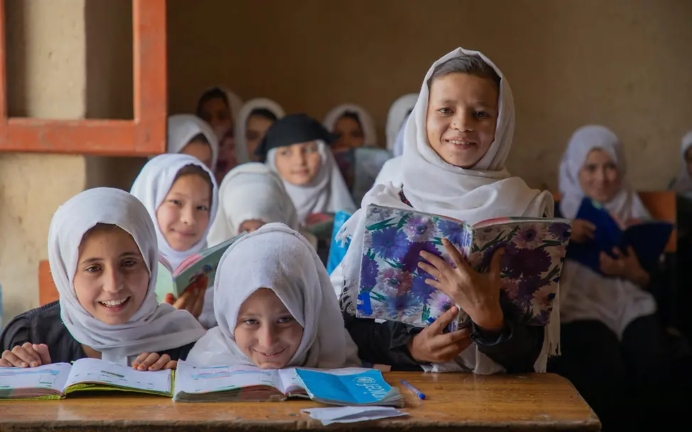 Let Us Learn UNICEF: Mädchen mit Schulheften in einem Klassenzimmer lächeln in die Kamera. 