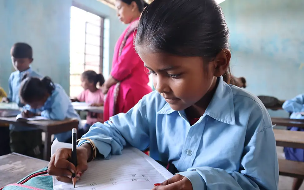 UNICEF setzt sich mit Let Us Lear auch für die Aus- und Weiterbildung von Lehrkräften in Nepal ein. | © UNICEF/Schreiber Let Us Learn in Nepal: Ein Mädchen sitzt in ihrer Schulklasse und schreibt in ein Schulheft.