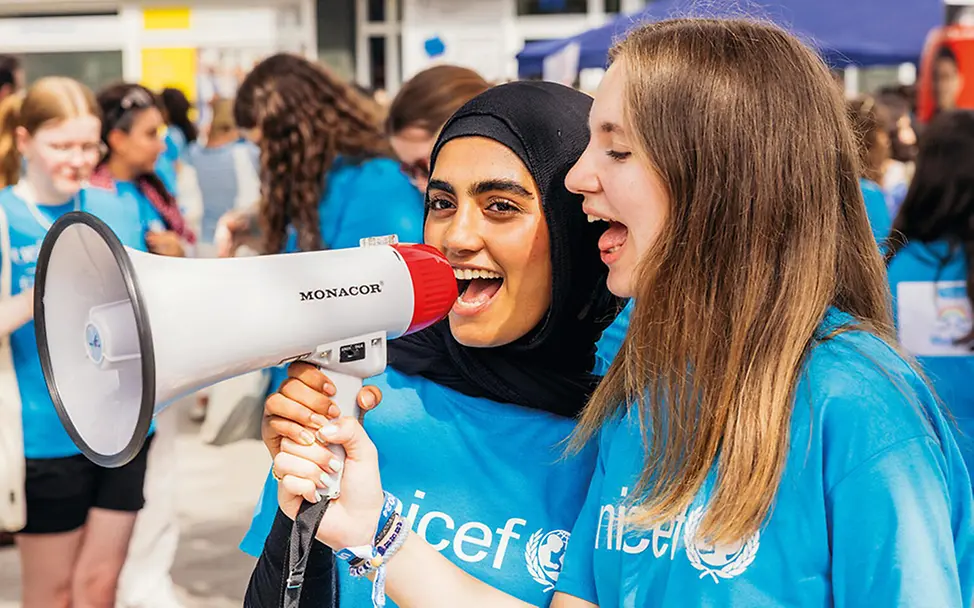 UNICEF setzt sich weltweit für Gerechtigkeit und gegen Diskriminierung von Kindern und ihren Familien ein. | © UNICEF/Stroisch Was kann man gegen Rassismus tun: Zwei Mädchen in UNICEF-Shirts sprechen in ein Megafon.
