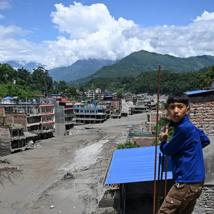 Ein Kind steht vor Häusern, die durch die Sturzflut in Nepal beschädigt wurden. | ARUN SANKAR / AFP Sturzflut Nepal: Ein Kind steht vor beschädigten Häusern