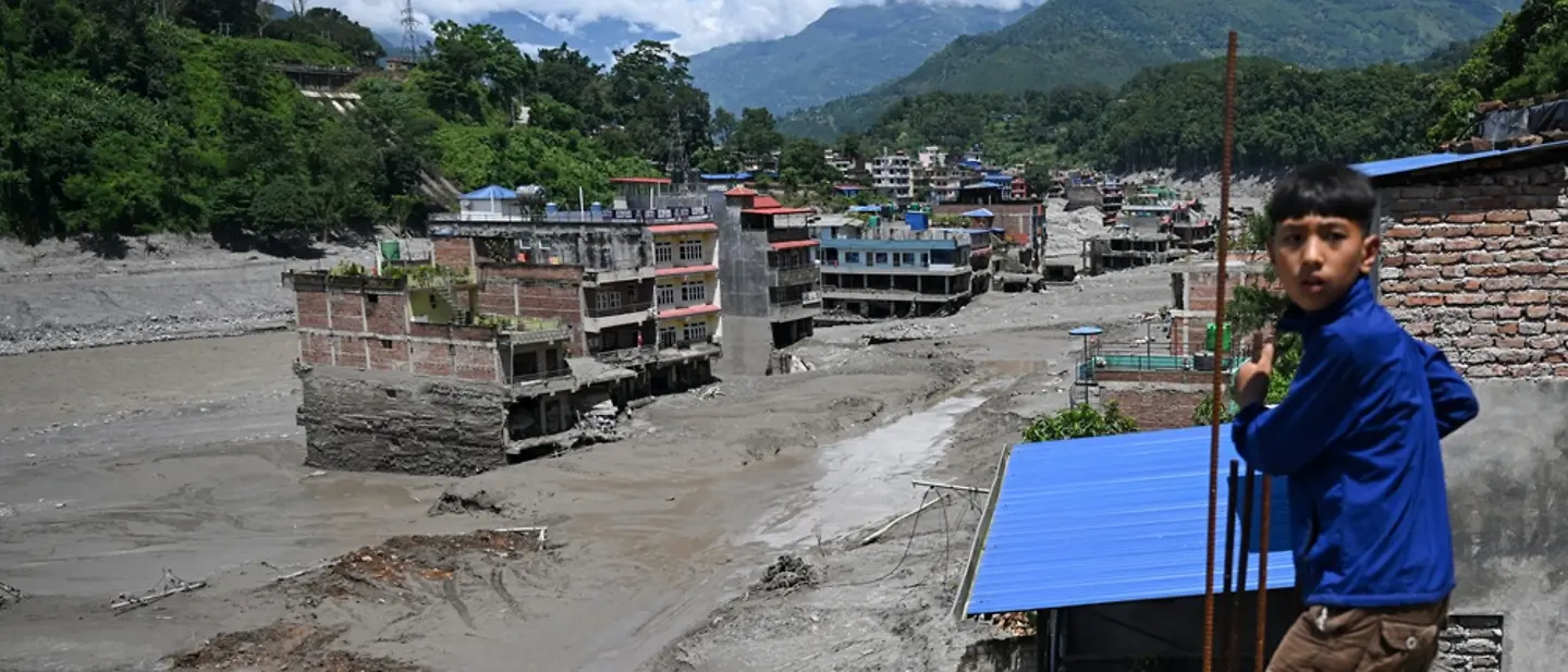 Sturzflut Nepal: Ein Kind steht vor beschädigten Häusern