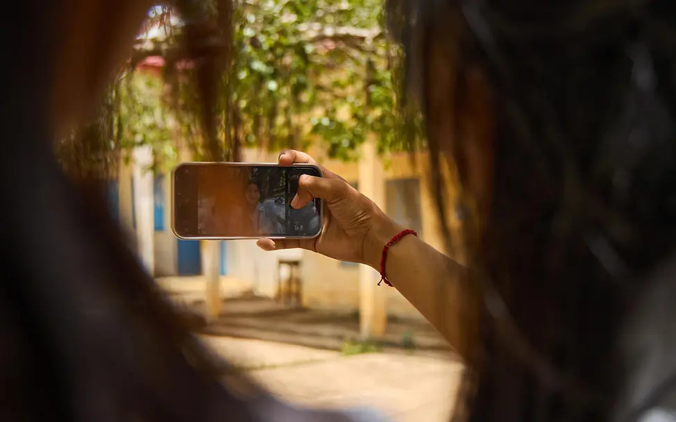 Viele Kinder und Jugendliche teilen Bilder, Videos und sogar Online-Passwörter mit Personen, die sie gar nicht kennen. | © UNICEF/Lloyd Missbrauch im Internet: Zwei junge Mädchen schauen auf ein Handy.