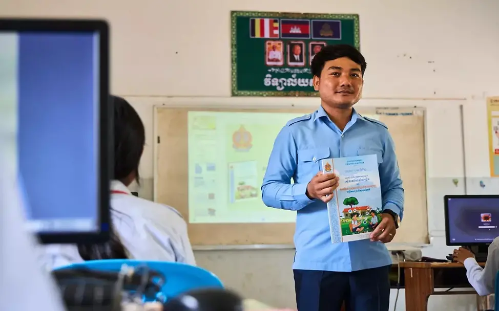 Frühe Aufklärung über Online-Risiken kann helfen, Kinder vor sexuellem Missbrauch im Internet zu schützen. | © UNICEF Cambodia/Seavhong Liv Missbrauch im Internet: Ein Lehrer steht mit einem Arbeitsheft vor einer Schulklasse.