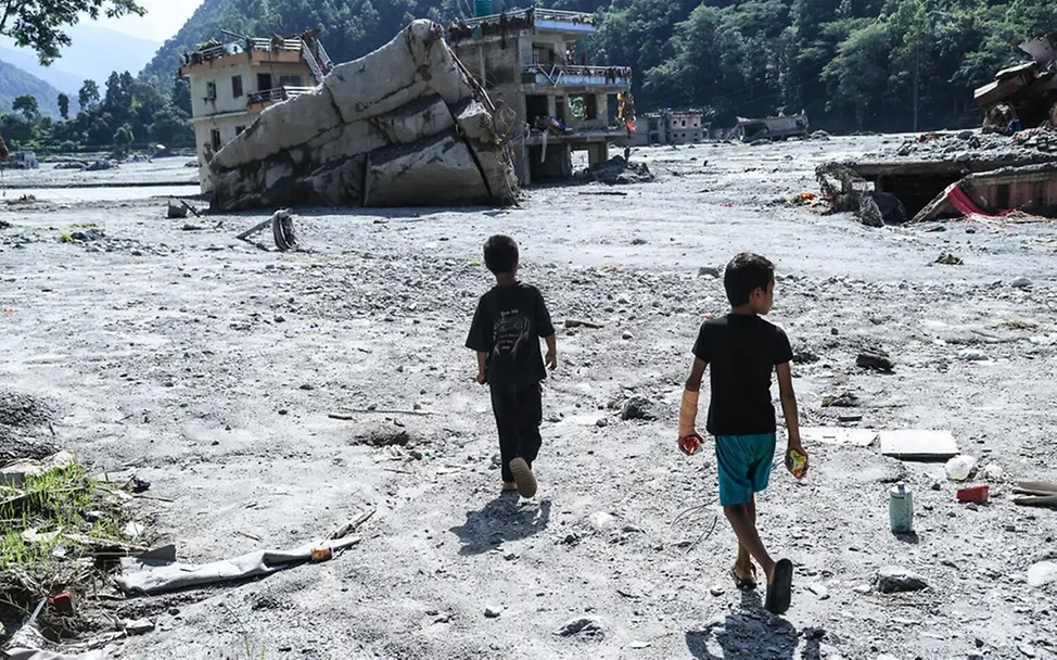 Kinder gehen über das durch verheerende Überschwemmungen zerstörte Gelände ihrer Schule. | © UNICEF/UN0921280/Laxmi-Prasad-Ngakhusi Kinder gehen über das durch verheerende Überschwemmungen zerstörte Gelände ihrer Schule.