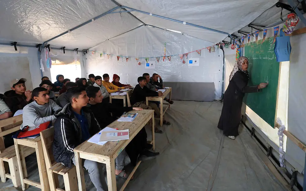 Mit Notschulen hilft UNICEF Kindern in Krisengebieten, damit sie lernen können. | © UNICEF/Eleyan Was ist Krieg einfach erklärt: Eine Lehrerin unterrichtet eine Schulklasse in einer Notschule.