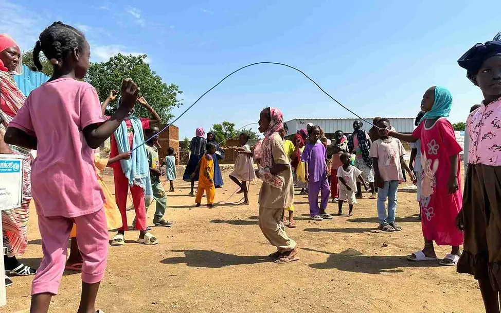 UNICEF richtet spezielle kinderfreundliche Orte ein, in denen Kinder Ruhe finden und unbeschwert spielen können. | © UNICEF/ Nakibuuka Was ist Krieg einfach erklärt: Kinder spielen im Freien Seilspringen.