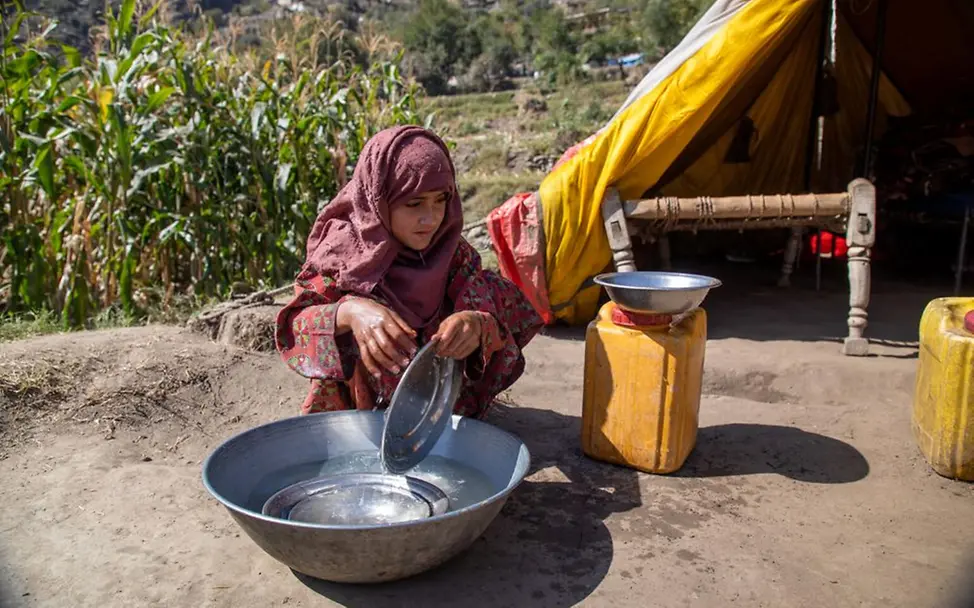 Ein Mädchen wäscht vor einem Zelt das Geschirr. | © UNICEF/Azizi Afghanistan Krise: Safia (10) sitzt vor einem Zelt und wäscht das Geschirr in einer großen Schüssel.