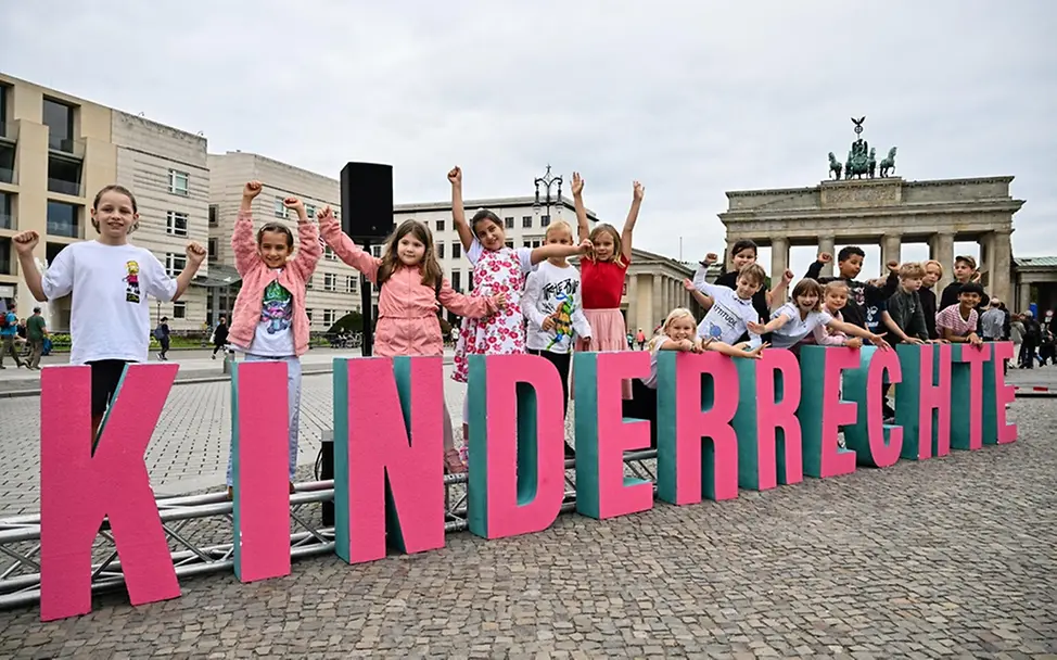 UNICEF setzt sich weltweit für die Rechte und den Schutz von Kindern ein. | © UNICEF/UNI864825/Paula G. Vidal Wahlen einfach erklärt: Kinder stehen mit einem „Kinderrechte“-Schriftzug vor dem Brandenburger Tor.