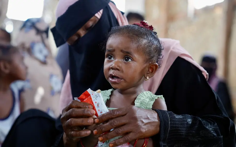 UNICEF liefert therapeutische Nahrung wie Erdnusspaste in den Jemen, damit mangelernährte Kinder wieder zu Kräften kommen. | © UNICEF/Waqqas Hunger im Jemen: Ein Kind auf dem Schoß seiner Mutter wird mit Erdnusspaste gefüttert.