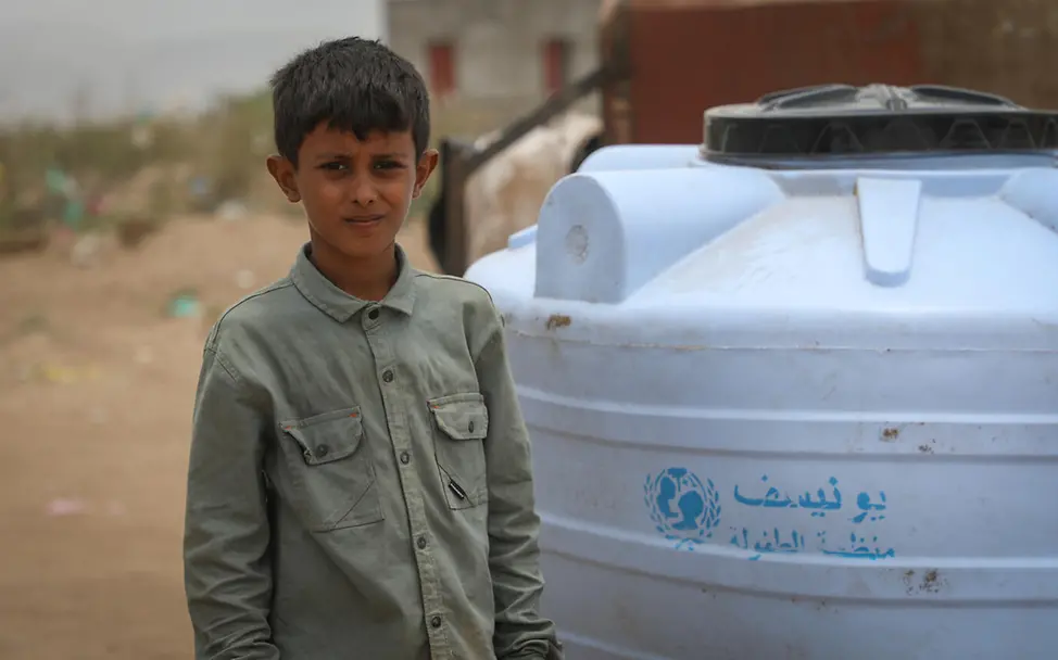 Sicheres Wasser ist entscheidend, um die Ausbreitung von Krankheiten im Jemen zu vermeiden. | © UNICEF/Al Qader Hunger im Jemen: Ein Junge steht im Freien vor einem Trinkwassertank.
