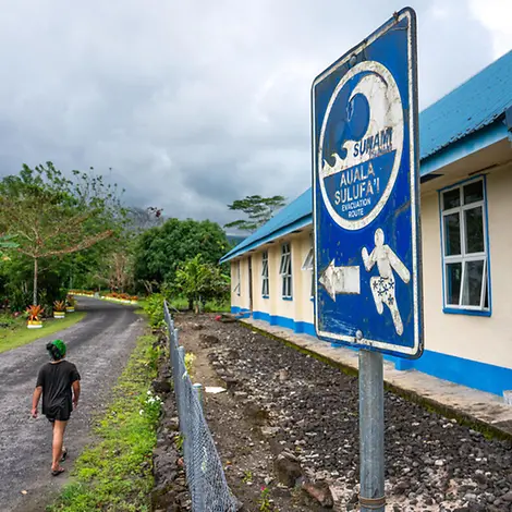 Das Hinweisschild zeigt die Evakuierungsroute im Fall eines Tsunamis. | © UNICEF/Ijazah Tsunami einfach erklärt: Ein Junge läuft an einem Hinweisschild für eine Tsunami-Evakuierungsroute vorbei.