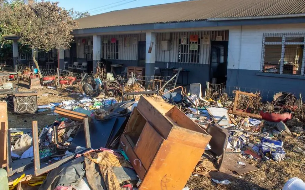 Überschwemmungen richten große Schäden an Wohnhäusern, Straßen und Schulen an | © UNICEF/Wolfgramm Was sind Tsunamis: Möbel, Hausrat und andere Gegenstände liegen vor einem überfluteten Schulgebäude.