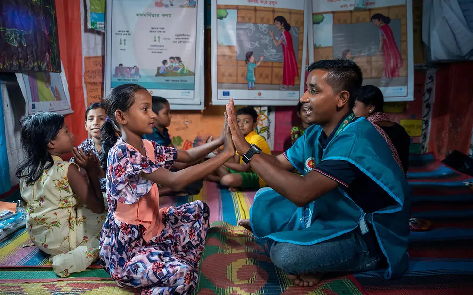 UNICEF leistet in Krisengebieten medizinische und psychologische Hilfe für Menschen in Not. | © UNICEF/Himu Was ist ein Tsunami: Ein UNICEF-Helfer spielt mit Kindern in einem Versorgungszelt.
