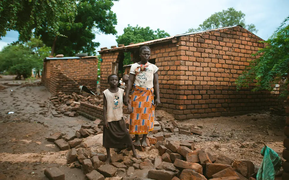 El Niño: Eine Mutter und ihre Tochter stehen in den Trümmern ihres Zuhauses | © UNICEF/PLUS CREATIONS El Niño: Erhebliche Regenfälle und Überschwemmungen brachten im Jahr 2024 Millionen Familien in Gefahr.