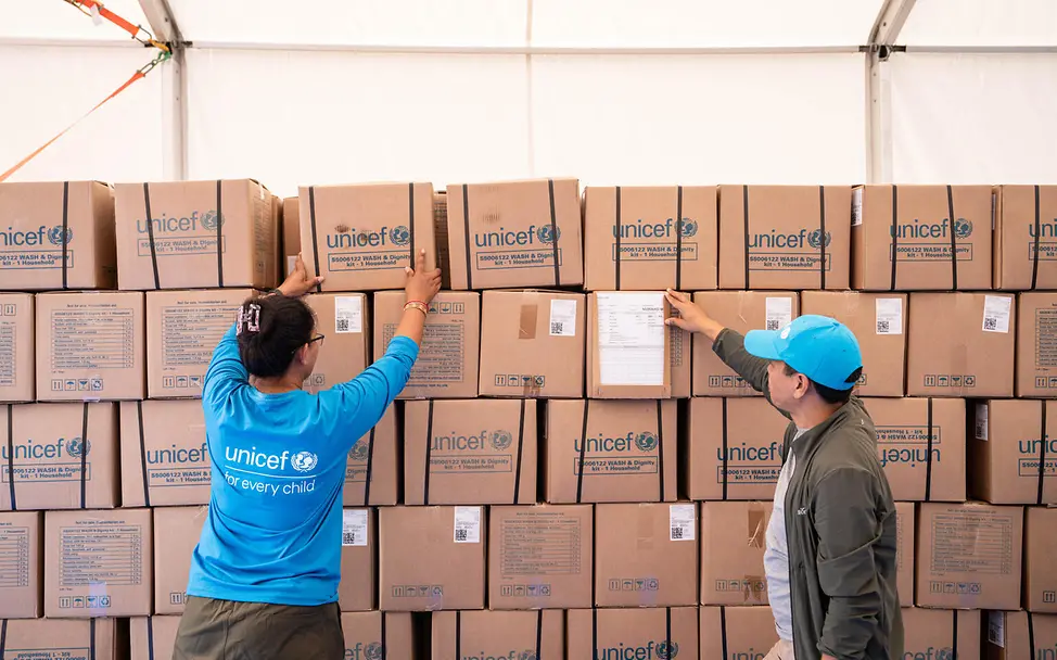 Ein UNICEF-Team sichtet in einem Warenlager die Kartons mit UNICEF-Hilfsgütern | © UNICEF/Upadhayay Nepal Sturzflut spenden: Zwei UNICEF-Mitarbeitende prüfen die im Katastrophengebiet angekommenen Hilfsgüter