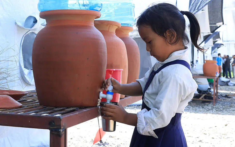 Ein Mädchen zapft an einer UNICEF-Wasserstation frisches Trinkwasser in einen Becher | © UNICEF/Prasad Ngakhusi Nepa spenden Sturzflut: Ein Mädchen zapft sich Wasser an einer von UNICEF bereitgestellten Wasserstation.