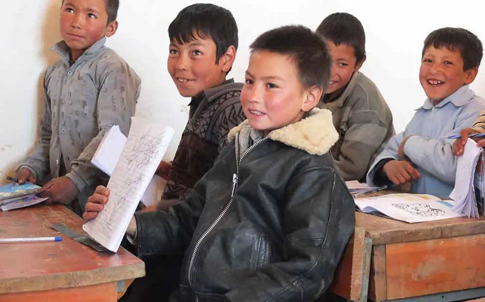 Besonders Kinder aus entlegenen Gebieten werden durch Let Us Learn gefördert | © UNICEF/Findel Afghanistan: Jungen in einer Schulklasse zeigen stolz, was sie geschrieben haben.