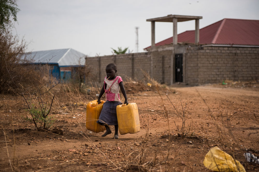Ein Mädchen auf dem Weg um Wasser zu holen | © UNICEF/Hatcher-Moore Südsudan: Ein Mädchen trägt Wasserkanister um sie mit Wasser zu füllen