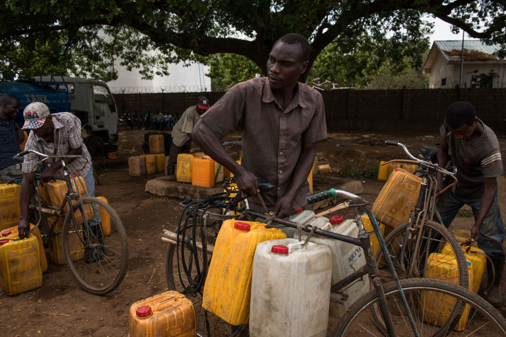 Ein Wasserverkäufer belädt sein Fahrrad mit Kanistern | © UNICEF/Hatcher-Moore Südsudan: Ein Wasserverkäufer bindet Wasserkanister an sein Fahrrad