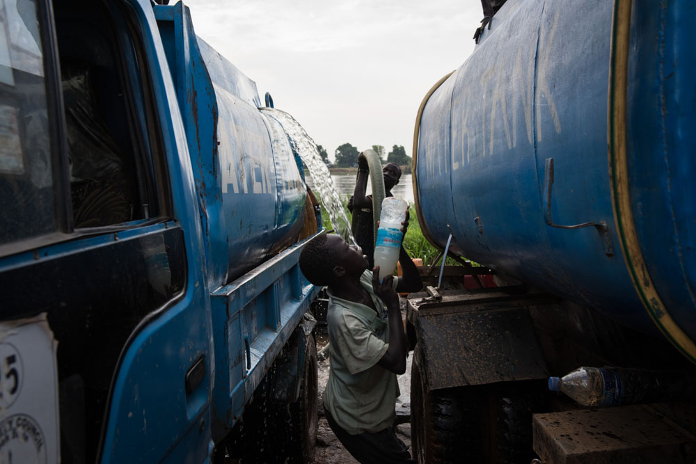 Der 13-jährige Francis steht zwischen zwei Wassertransportern | © UNICEF/Hatcher-Moore Südsudan: Francis steht zwischen zwei Wassertransportern