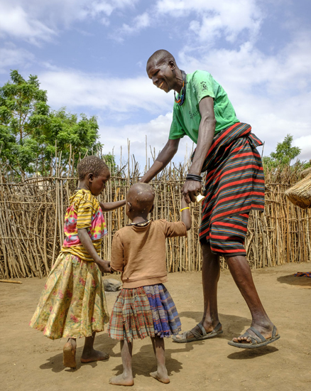 Uganda: Ein Vater tanzt mit seinen beiden Kindern im Freien