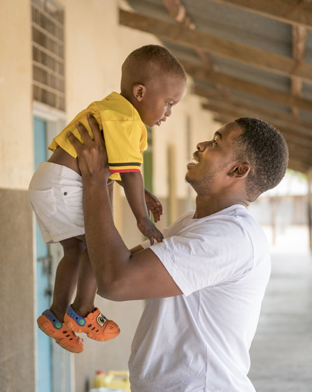 Mark hält seinen 22 Monate alten Sohn in die Luft | © UNICEF/Ose Uganda: Ein Vater hält seinen Sohn hoch in die Luft