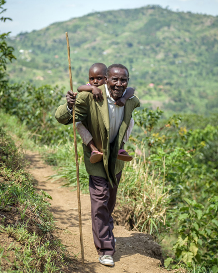 Die 3-jährige Asinet wächst bei ihrem Großvater auf | © UNICEF/Ose Uganda: Asinet wird von ihrem Großvater auf dem Rücken getragen