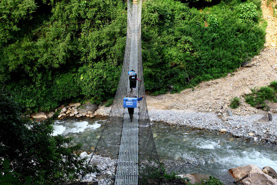 Die Träger überqueren in Nepal einen Fluss | © UNICEF/Panday Nepal: Zwei Träger überqueren einen Fluss über eine Brücke