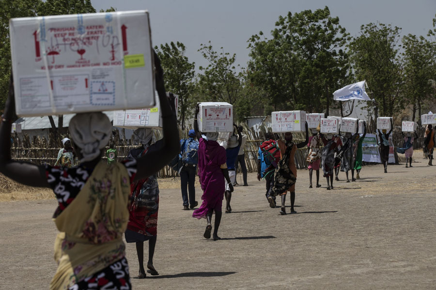 Südsudan: Frauen transportieren Kisten mit Impfstoffen durch die Straßen