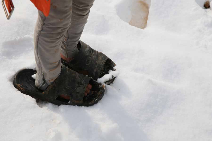 Ein syrisches Flüchtlingskind steht in viel zu großen Sandalen im Schnee in einem Zeltlager für Flüchtlinge im Libanon. | © UNICEF/Dar Al Mussawir Ein Flüchtlingskind steht in viel zu großen Sandalen im Schnee.