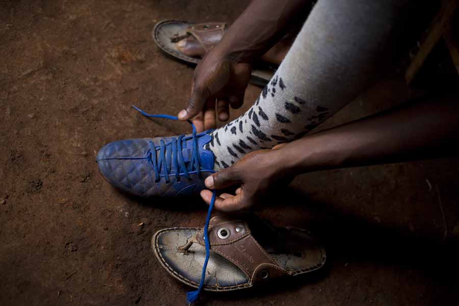 Der 17-Jährige Jean-Pierre schnürt seine Fußballschuhe. | © UNICEF/Prinsloo Burundi: Der 17-Jährige Jean-Pierre schnürt seine Fußballschuhe.