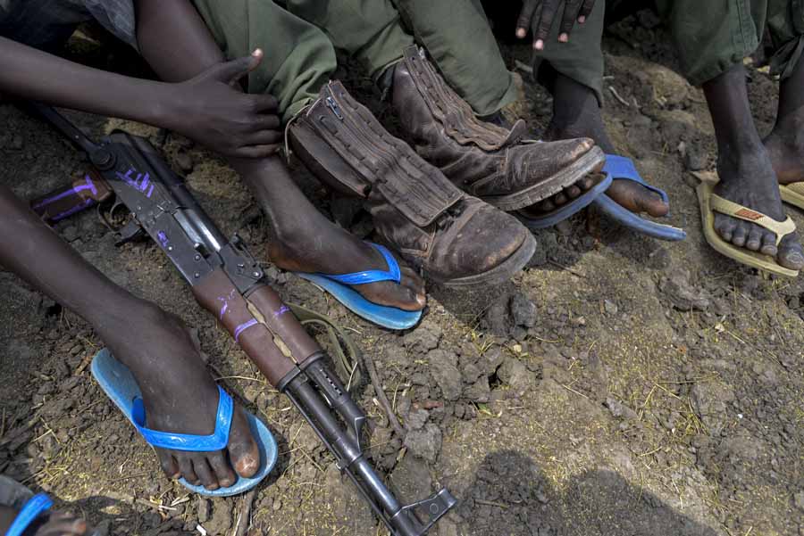 Südsudan: Zwischen den Füßen von Kindersoldaten liegt eine Waffe.