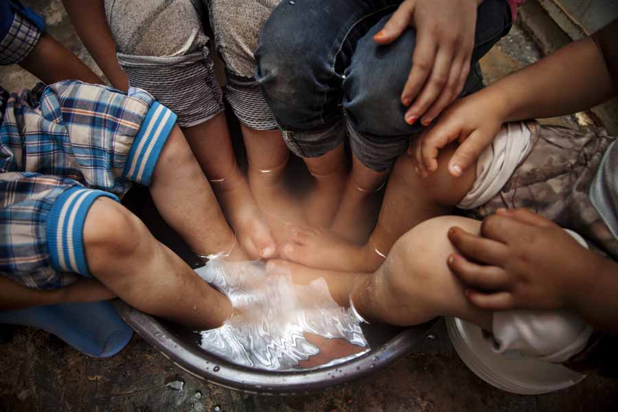 Auch die kleinen Füße müssen sich mal erholen. | © UNICEF/Gilbertson VII Photo Jordan: Vier Kinder erholen sich mit einem Fußbad.