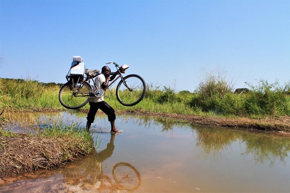 UN0217108 kongo fahrrad Kongo: Ein Impf-Helfer trägt sein Fahrrad über einen Fluss