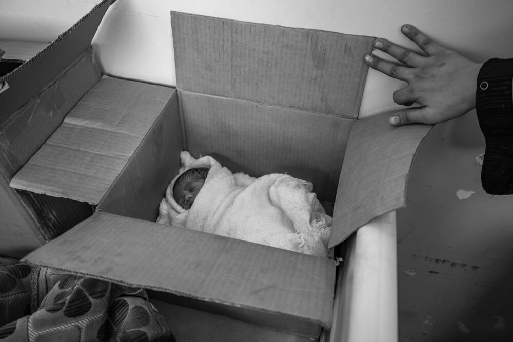 Eines der Zwillingskinder schlafend in einem Karton | © Giles Clarke for UNOCHA Jemen: Kind liegt schlafend in einem Karton