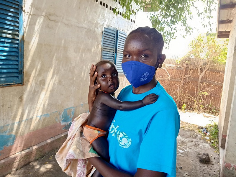 Südsudan: UNICEF-Kinderreporterin hält Neugeborenes auf dem Arm.
