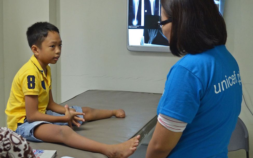 Umgang mit Behinderung: Auf den Philippinen spricht UNICEF-Mitarbeiterin Peewee mit Adam.