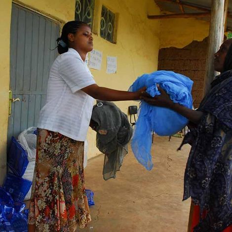 Eine UNICEF-Helferin verteilt Moskitonetze 